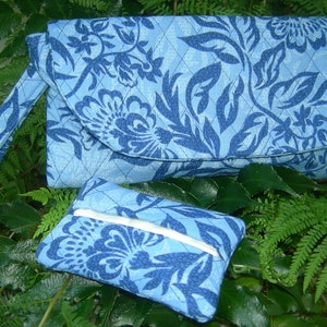 K&ouml;nnte beinhalten: Eine blaue gesteppte Clutch mit Blumenmuster und einer passenden kleineren Tasche. Die Clutch hat einen langen Riemen.