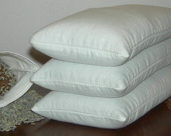 May include: Four white pillowcases filled with dried lavender and grains. The pillowcases are stacked on top of each other. The dried lavender and grains are spilling out of the pillowcases.