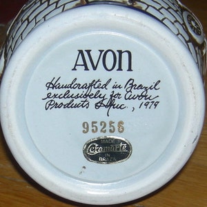 May include: White ceramic Avon bottle with a blue and white design. The bottom of the bottle has the text "AVON", "Handcrafted in Brazil exclusively for Avon Products Afric, 1979", "95256", and "Made in Brazil" with the Cramarle logo.