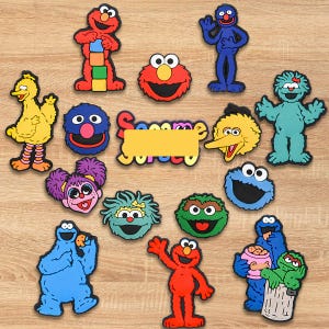 May include: A collection of colorful Sesame Street character magnets, including Elmo, Cookie Monster, Big Bird, and others. The magnets are in various shapes and sizes, with vibrant colors and recognizable features. A yellow sign with the word "Sesame" is also present.
