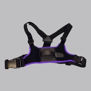 May include: A black chest harness featuring purple trim, adjustable black straps, and a central black plastic buckle. The harness includes a small horizontal strap across the center with the text VYNOUR printed in white on a small black tab.