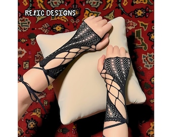 Pode incluir: Luvas pretas sem dedos com design de rede e detalhes recortados. As luvas têm um design de cadarço no pulso e no antebraço. O texto "RELIC DESIGNS" é visível no canto superior esquerdo.