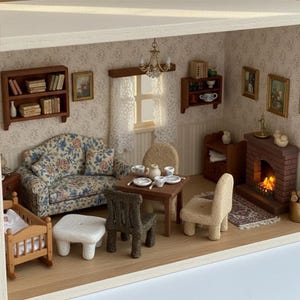 May include: A miniature dollhouse living room featuring a floral sofa, a wooden dining table with tea set, two textured chairs, a white stool, a wooden cradle, a brick fireplace with a fire effect, wall shelves with books, and lace curtains.