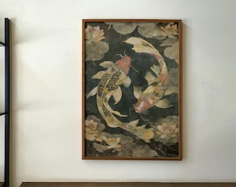 May include: A framed artwork featuring two koi fish swimming in a circle, surrounded by lily pads and flowers. The fish have orange, yellow, and black markings. The artwork is in a wooden frame and hangs on a cream-colored wall.