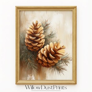 Può includere: Una stampa incorniciata con due dettagliate pigne nei toni del marrone e dell'oro, su uno sfondo morbido e neutro. L'opera d'arte include aghi di pino verdi ed è racchiusa in una cornice color oro. Il testo "WillowDustPrints" è in basso.