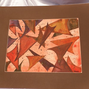 May include: Abstract watercolor painting featuring overlapping geometric shapes in shades of orange, red, and brown, with a light pink background and brown matting. The artwork has a modern aesthetic.