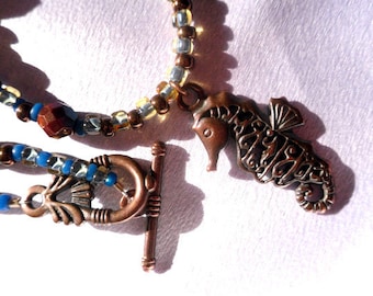 Collar con cuentas de bronce, cobre, marrón y azul con temática del océano con ojo de tigre y colgante de caballo de mar