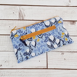May include: A small blue zippered pouch with a floral pattern in white, yellow, and blue. The pouch has two zippers.