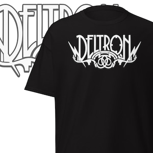 May include: Black t-shirt featuring the white text "DELTRON" in a decorative font. The design incorporates lightning bolts and a circular emblem. The shirt is a short-sleeved crew neck.