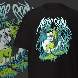Puede incluir: Camiseta negra con un diseño en verde neón y azul de una criatura parecida a un ciervo con alas de murciélago, sobre una superficie rocosa. El texto "AESOP ROCK" se muestra encima de la criatura en una fuente estilizada.