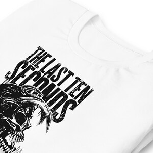 May include: White t-shirt with a black skull graphic and the text "THE LAST TEN SECONDS". The design is in a distressed style. The shirt is made of a soft material.