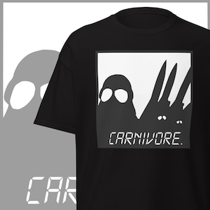 May include: Black t-shirt with a white graphic featuring silhouettes of two figures and the word "CARNIVORE" in a digital font. The design is centered on the chest.