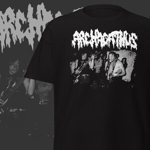 May include: Black t-shirt featuring the band name "ARCHAGATHUS" in white, stylized text above a black and white image of a band performing on stage. The shirt has a crew neck and short sleeves.