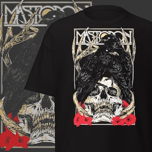 May include: Black t-shirt featuring a graphic design with the band name "Mastodon" at the top. The design includes a skull, ravens, antlers, and red flowers. The shirt is a crew neck.