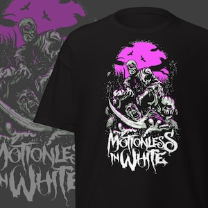 Może przedstawiać: Czarna koszulka z grafiką o tematyce zombie. Projekt zawiera różowy księżyc, szkieletowe postacie i nazwę zespołu "Motionless in White" w białych literach. Projekt jest również odbity po lewej stronie.