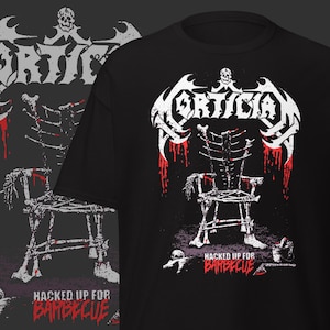 Puede incluir: Camiseta negra con un diseño gráfico blanco y rojo. El diseño incluye la palabra "Mortician" sobre una silla esquelética con goteo de sangre. La frase "Hacked Up For Barbecue" está impresa debajo.