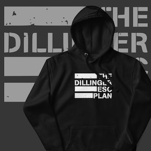 Może przedstawiać: Czarna bluza z kapturem z białym napisem "THE DILLINGER ESCAPE PLAN" i "THE DILLINGER ESCAPE PLAN" w prostokącie. Tło jest szare z napisem "DILLINGER" dużymi, zniszczonymi literami.