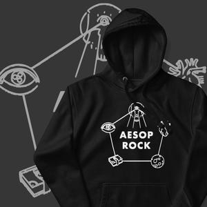 以下が含まれることがあります： 黒色のフード付きスウェットシャツ。白いグラフィックデザインで、「AESOP ROCK」の文字が五角形の中に配置されています。目と頭蓋骨のイラストが線で繋がれています。背景は濃いグレーです。
