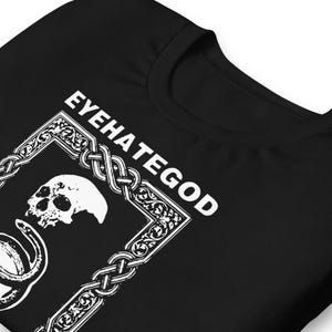 May include: Black t-shirt with the white text "EYEHATEGOD" above a white skull and snake graphic. The graphic is framed by a decorative border. The shirt is made of a soft material.