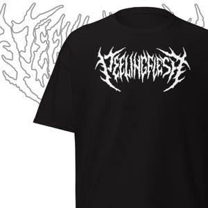 May include: Black t-shirt with the white text "FEELINGFLESH" in a gothic font. The shirt has short sleeves and a crew neck. A white, abstract design is visible on the left side of the shirt.