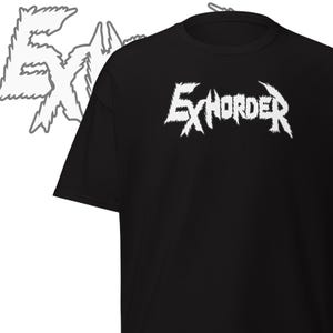 May include: Black t-shirt with the white text "EXHORDER" in a jagged, stylized font. A matching white graphic is visible to the left of the shirt. The shirt is a basic crew neck style.