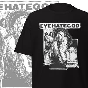 May include: Black t-shirt with the text "EYEHATEGOD" in a white rectangular box. The shirt features a black and white graphic of a skeletal figure holding a child, with other figures in the background.