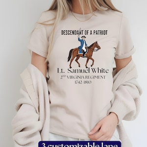 May include: Beige t-shirt featuring a graphic of a man on horseback in a blue coat, with the text "Descendant of a Patriot" and "Lt. Samuel White 2nd Virginia Regiment 1742-1810". The bottom of the shirt has the text "3 customizable lane".