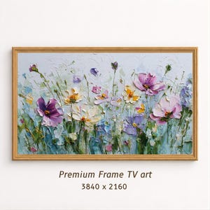 Può includere: Dipinto floreale incorniciato con una cornice color oro. L'opera presenta uno stile impasto strutturato, raffigurante fiori colorati nelle tonalità del viola, rosa, giallo e bianco su uno sfondo azzurro. Il testo "Premium Frame TV art" è in basso.