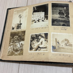 May include: A vintage photo album page featuring six black and white photographs arranged in a grid. The images depict a windmill, potted plants, two children, a landscape, a person sitting outdoors, and a path. Handwritten notes appear below each.
