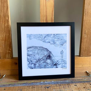 May include: A framed black and white pen and ink drawing of a landscape with a figure. The artwork features a detailed rendering of a hill or mountain, clouds, and a person standing in the distance. The drawing is signed in the lower right corner.