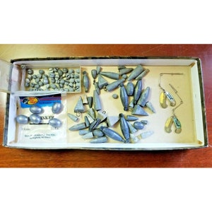 May include: A box of fishing sinkers and lures. The box contains a variety of sizes and shapes of lead sinkers, as well as two fishing lures. The box is labeled "Bass Pro Shops Tournament Series Sinker 1/4 oz. 12 pc."