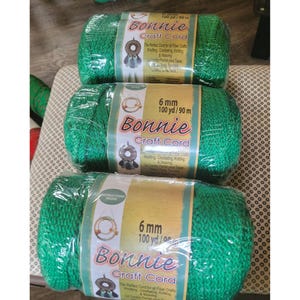 May include: Three spools of green Bonnie Craft Cord, each wrapped in clear plastic. The labels indicate the cord is 6 mm thick and 100 yards long. The packaging suggests the cord is suitable for knitting, crocheting, and weaving.
