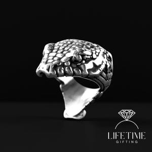 May include: A silver-colored ring in the shape of a snake's head, with detailed scales and open mouth. The ring is set against a black background. The text "LIFETIME GIFTING" is at the bottom.