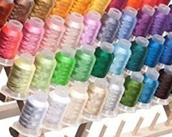 May include: A wooden thread rack with multiple spools of colorful embroidery floss. The rack has three tiers and is designed to hold and organize spools of thread.