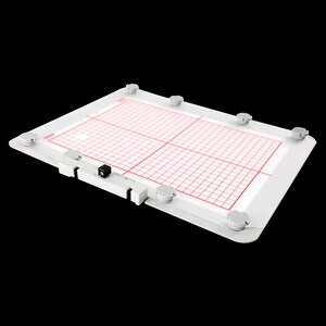 Op de afbeelding: Witte lichttafel met een rasterpatroon en rode lijnen. De tafel heeft acht witte rubberen voetjes en een zwarte camera die aan de zijkant is gemonteerd.