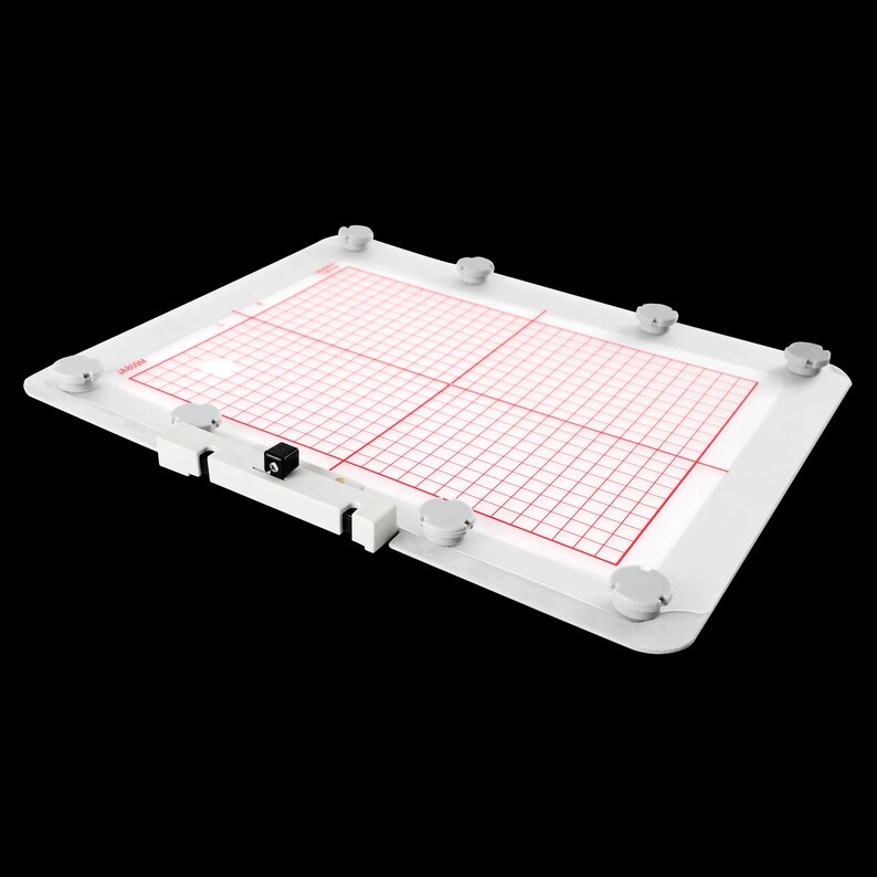 Op de afbeelding: Witte lichttafel met een rasterpatroon en rode lijnen. De tafel heeft acht witte rubberen voetjes en een zwarte camera die aan de zijkant is gemonteerd.