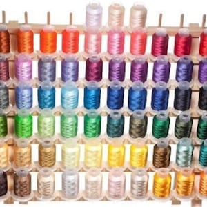 May include: A wooden thread rack with 72 spools of embroidery floss in various colors. The spools are arranged in rows and columns on the rack.