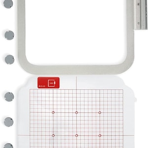 May include: A white embroidery hoop with a clear plastic template inside. The template has a grid pattern with red lines and red dots. The hoop is 5x7 inches and has a silver metal latch.