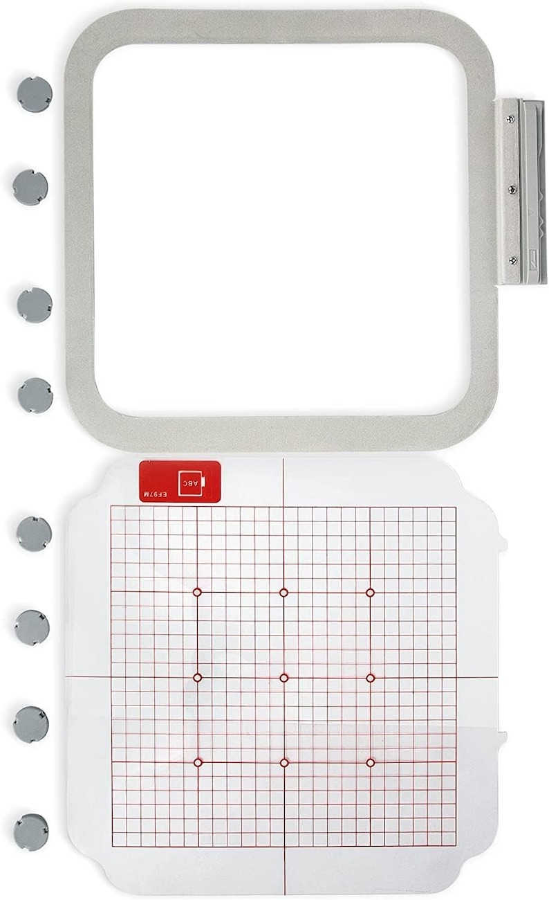 May include: A white embroidery hoop with a clear plastic template inside. The template has a grid pattern with red lines and red dots. The hoop is 5x7 inches and has a silver metal latch.