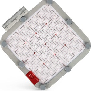 May include: A gray embroidery hoop with a white grid and red dots. The hoop has a silver metal frame and a red label that says "E-P97M ABC".