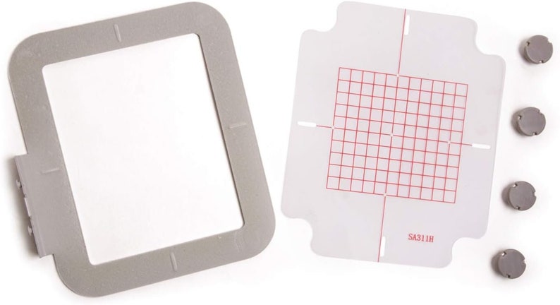 Puede incluir: Un aro de bordado gris con una plantilla de pl&aacute;stico transparente que presenta un patr&oacute;n de cuadr&iacute;cula y el texto "SA311H". Se incluyen cuatro discos magn&eacute;ticos grises.