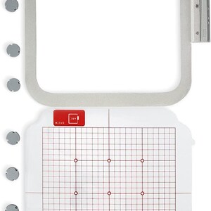 May include: A white embroidery hoop with a clear plastic template inside. The template has a grid pattern with red lines and red dots. The hoop is 5x7 inches and has a silver metal latch.