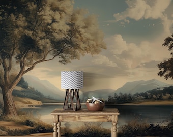 May include: A scenic landscape mural with a lake, trees, and mountains. A wooden table holds a lamp with a gray and white chevron pattern shade and a wooden base. A bowl with decorative items sits on the table.