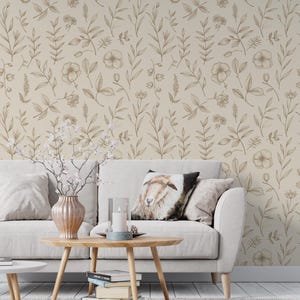 May include: A living room scene featuring a beige sofa with decorative pillows, a wooden coffee table, and a vase with flowers. The wall is covered in wallpaper with a repeating floral pattern in shades of brown and beige.