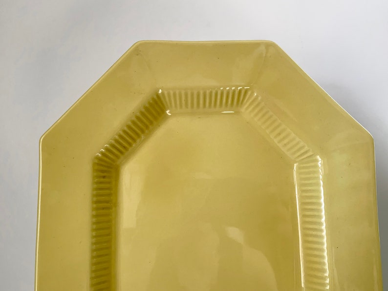 May include: A yellow octagonal serving platter with a raised, textured rim.