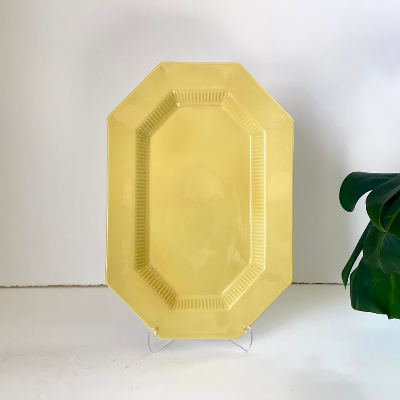 May include: A yellow octagonal ceramic serving platter with a raised rim and a textured surface.