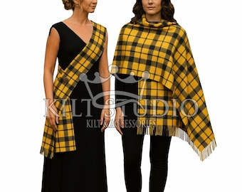 May include: Two women wearing black outfits with yellow and black plaid accessories. One woman has a sash, the other a shawl. The accessories have a fringed edge. The text "Kilt Studio Kilt Accessories" is visible.