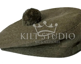 May include: Olive green Scottish Glengarry bonnet with a dark pompom on top. The hat has a structured brim and a small strap detail. The text "KILT STUDIO KILT & ACCESSORIES" is printed on the hat.