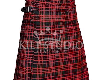 May include: A red and black plaid kilt with two black leather straps and buckles. The kilt has a pleated design and features the text "KILT STUDIO" and "KILTS & ACCESSORIES".