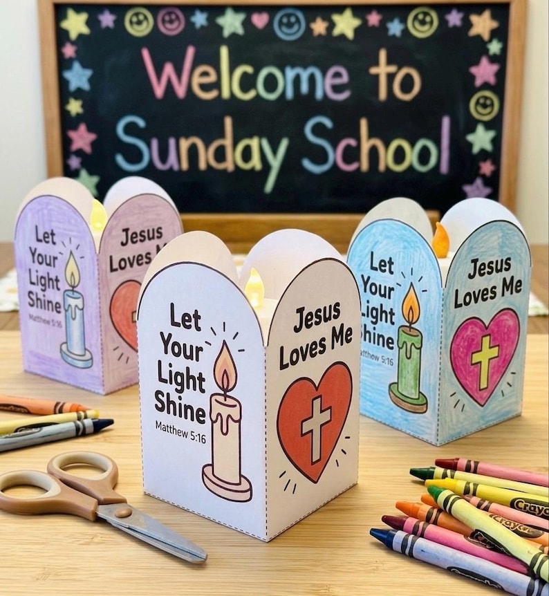 May include: Three paper lanterns featuring hand-colored illustrations of a candle and a heart with a cross. Each lantern displays the text Let Your Light Shine, Matthew 5:16, and Jesus Loves Me. The lanterns are arranged with crayons and scissors.
